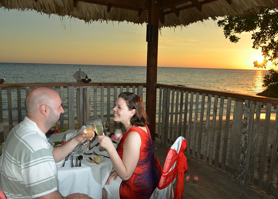A couple having a romantic dinner on a porch overlooking the ocean