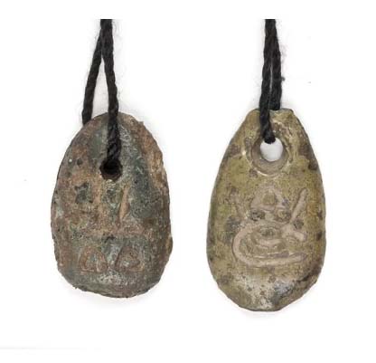 Two carved stone pendants with a hole at the top of each, suspended from a strip of leather.