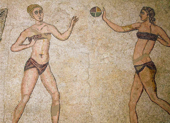 A mosaic in browns of two women in bikinis tossing a ball.