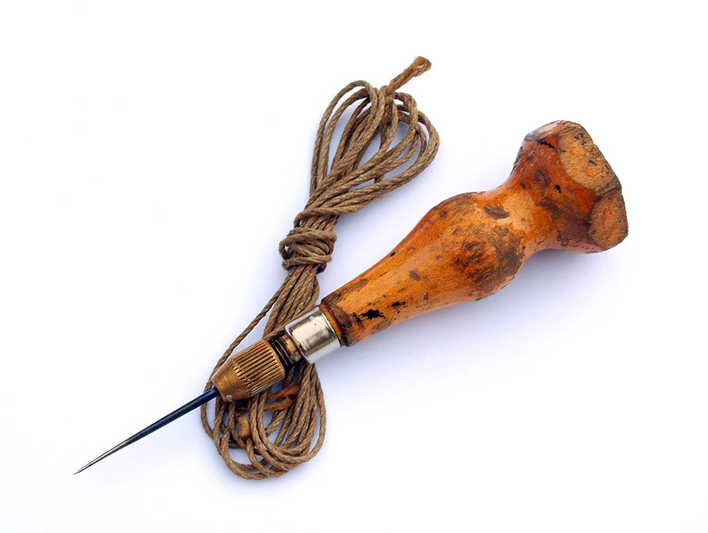 A battered wood-handled awl with a hank of string