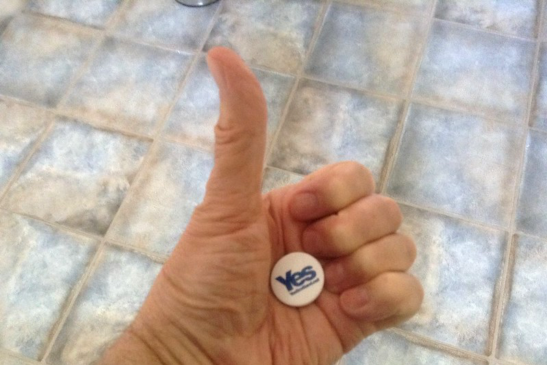 A hand against a tiled floor giving the thumbs up with a yes button in the palm of the hand