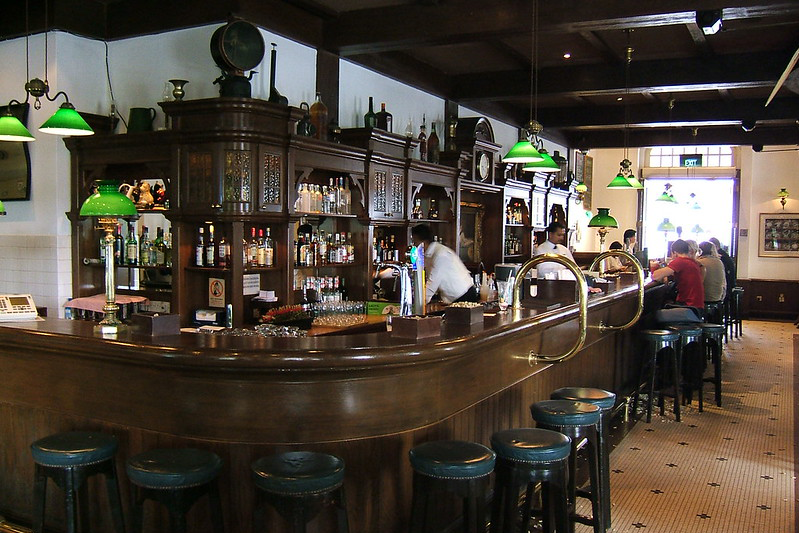 A curved wooden bar with an elaborate shelf display in the back