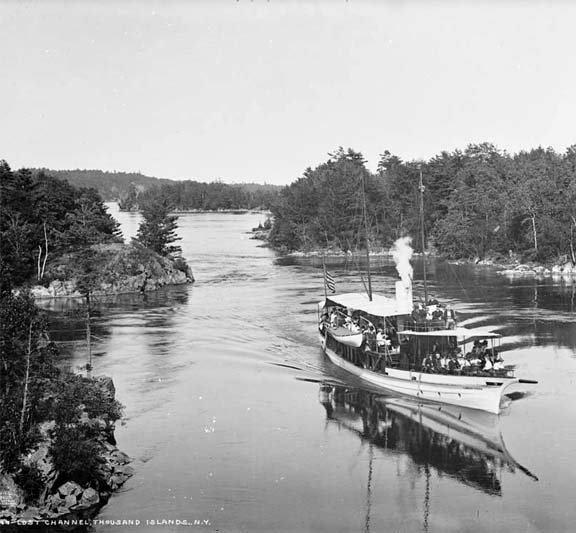 A black-and-white transparency of a ship steaming along in a curvaceous water channel bordered on both sides by forest.
