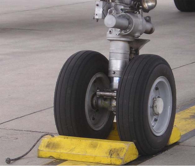 Close-up of an airplane wheel with chocks on either side of them.