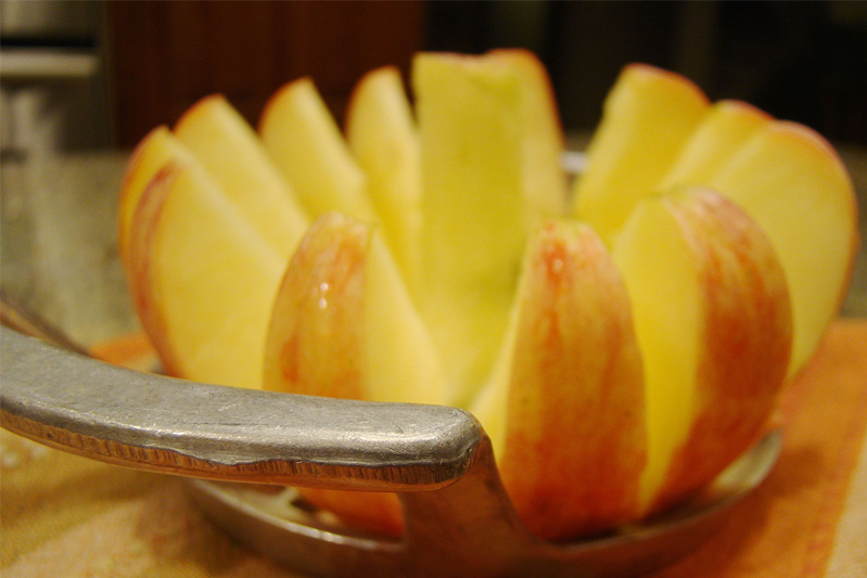Close-up of a metal apple corer having been pushed through an apple into slices