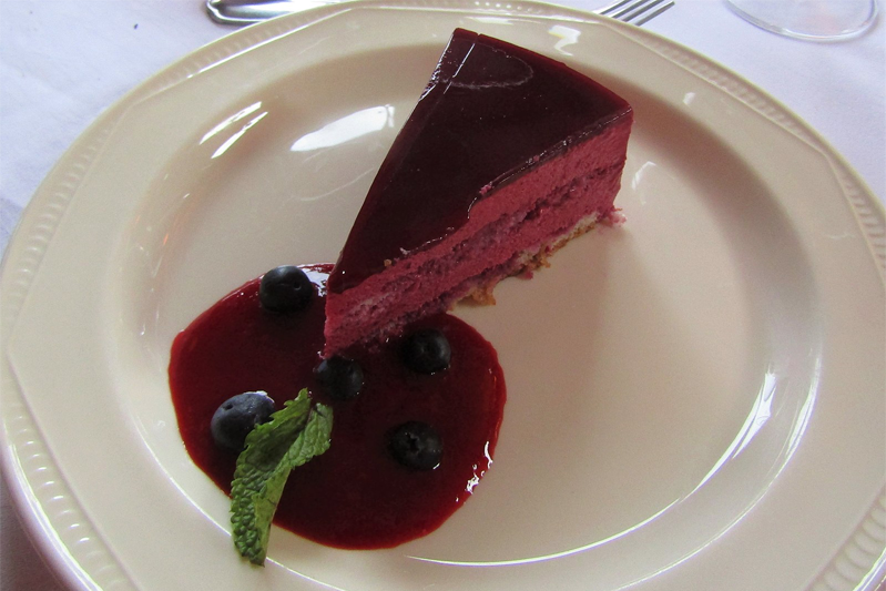 A blackcurrant mousse sponge cake served with red fruit coulis, prepared in a kitchen in the village of Trimingham, Norfolk, United Kingdom.