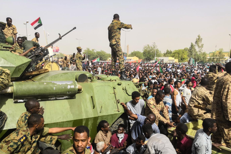 Sudanese soldeirs stand guard around armoured military vehicles as demonstrators continue their protest against the regime near the army headquarters in the Sudanese capital Khartoum