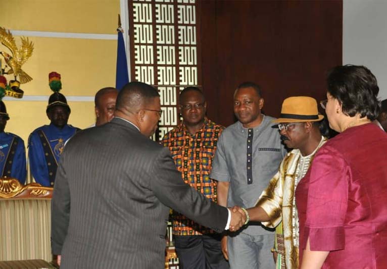 A line-up of people with one man shaking the hand of another.