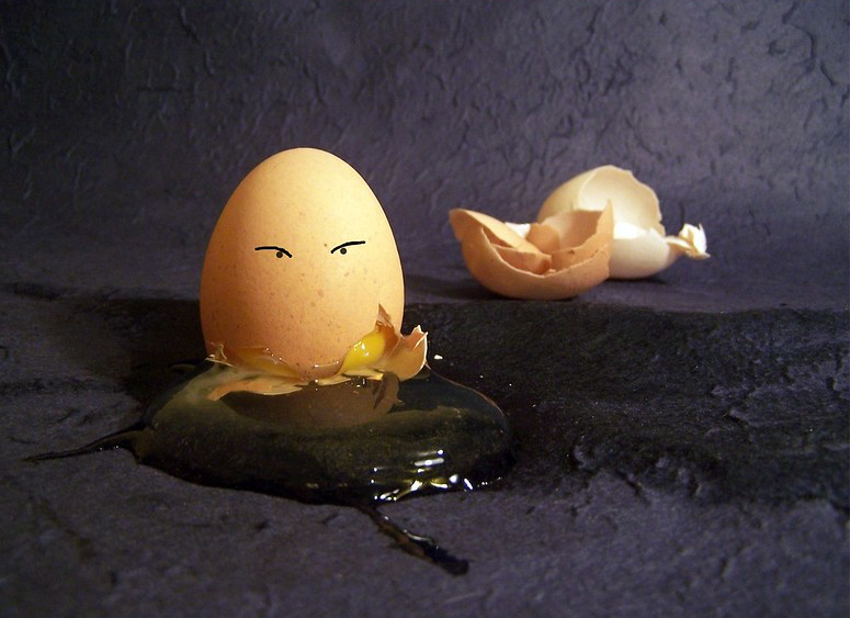Brown egg with penned-in eyes is broken on the floor