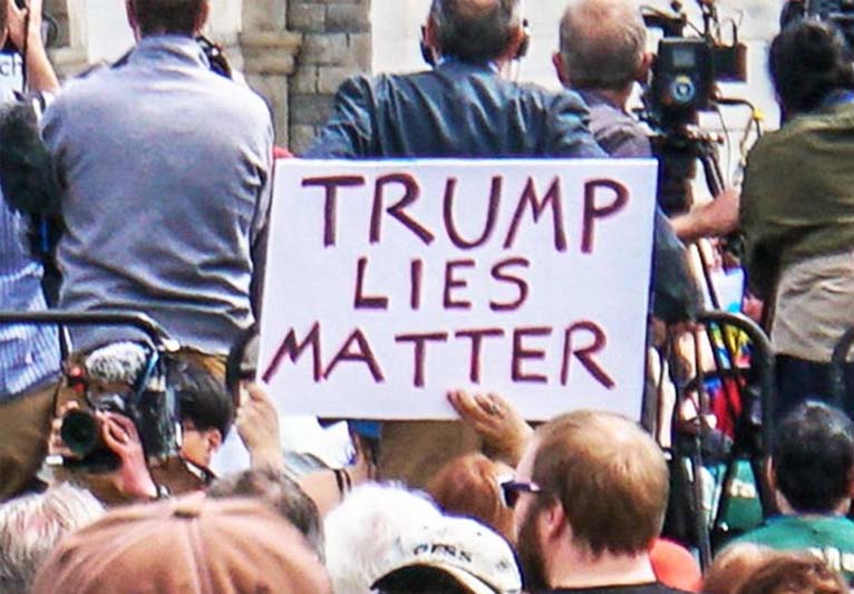 Amongst a crowd of people a sign reads Trump Lies Matter.