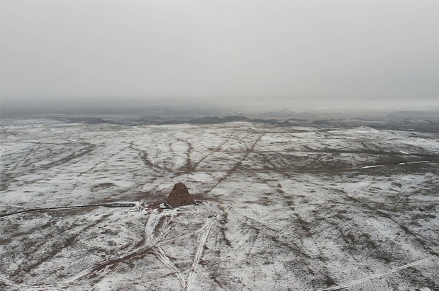 A grayed photo of a 60-ft. high pyramid stands desolate on a barren, windswept ridge in Wyoming.