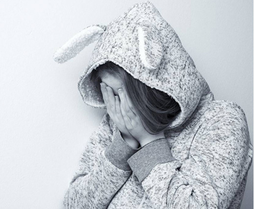 A woman in a bunny suit covering her face.