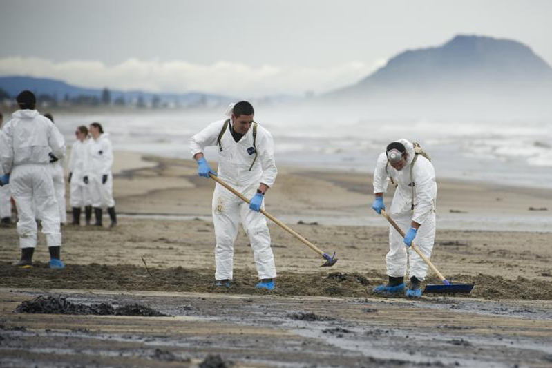 People in hazmat suits cleaning up a beach