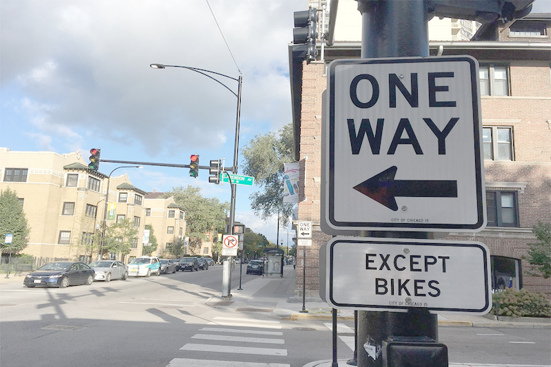A sign posting stating that this is a one way street except bikes can go either direction.