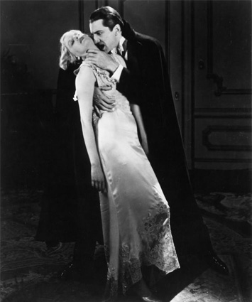 A woman in a long white gown is held tightly by Dracula who is eyeing her neck.