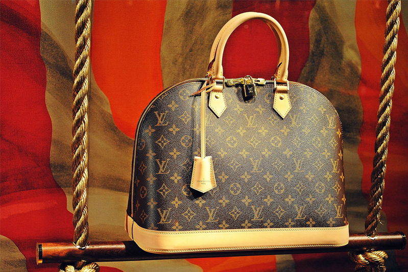A Louis Vuitton Speedy 30 handbag against a red background