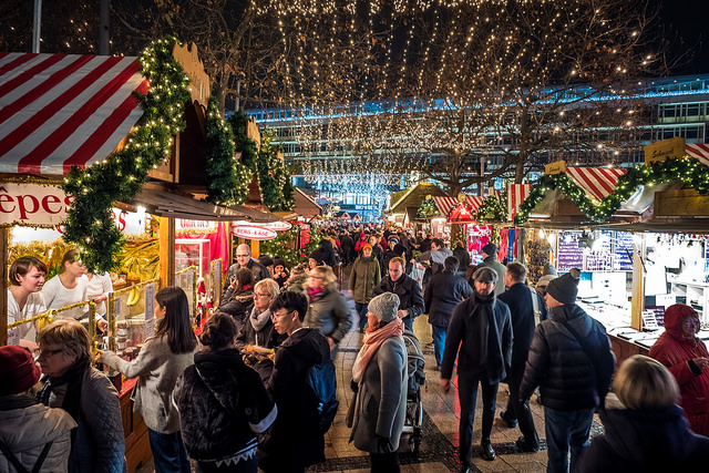 A nighttime Christmas Market with fairy lights strung overhead between booths
