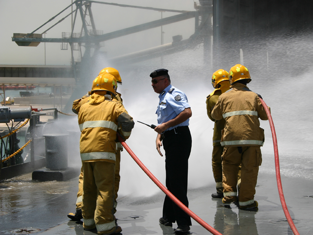 Four firemen in suits discuss the drill with a Kuwaiti official.