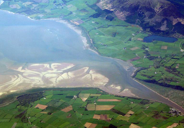 A view of the Nith estuary from the north-east. The group of buildings at bottom right is the village of Glencaple. At bottom left near the wooded area is Caerlaverock Castle. At top right is Loch Kindar and the hill above is called Criffel. Just beyond the top left of photo is the birthplace of John Paul Jones.