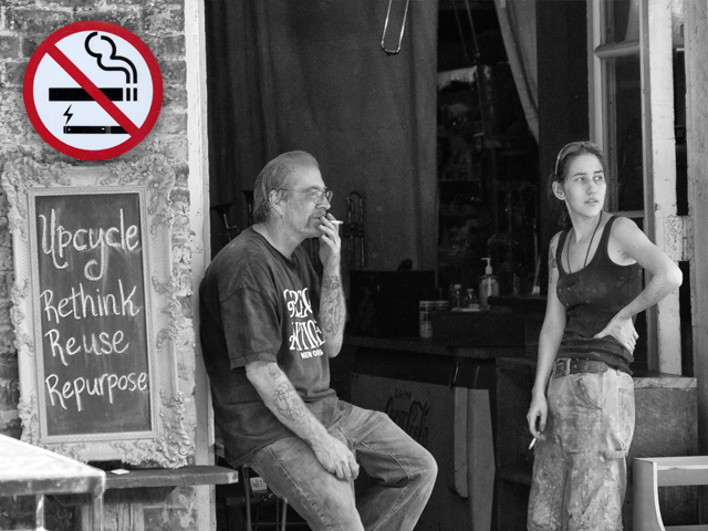 Black and white photograph of a man and woman smoking with a no smoking sign added on the left