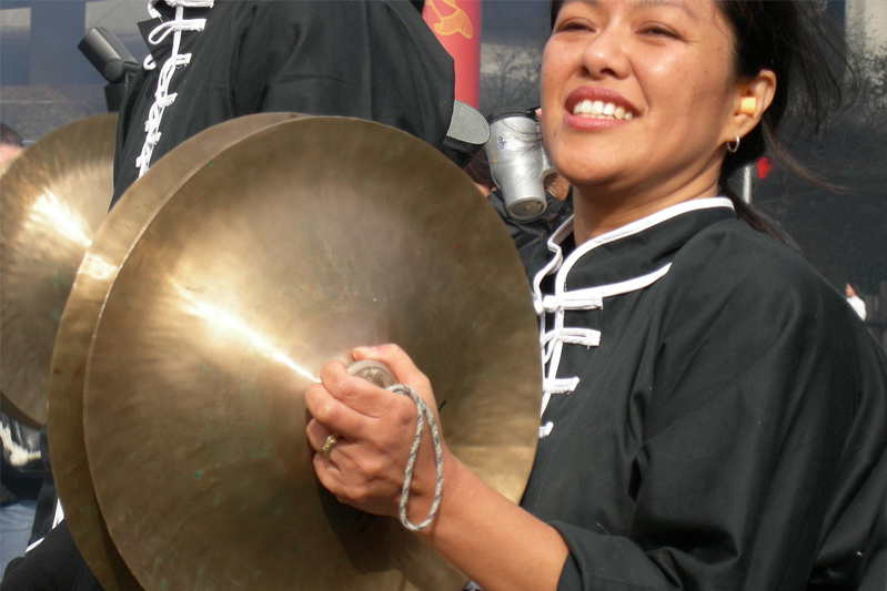 Chinese woman enthusiastically crashes her cymbals together.