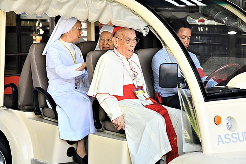 Pope Francis riding in the front passenger seat of a golf cart with two nuns in the back seat.