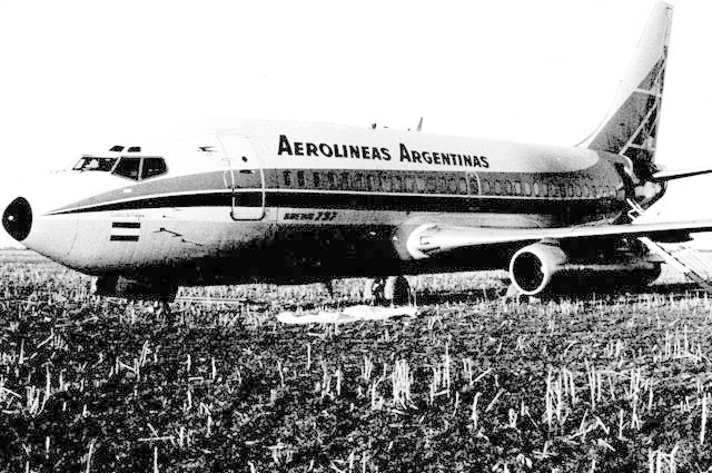 A black-and-white photo of a Boeing 737 in an empty field.