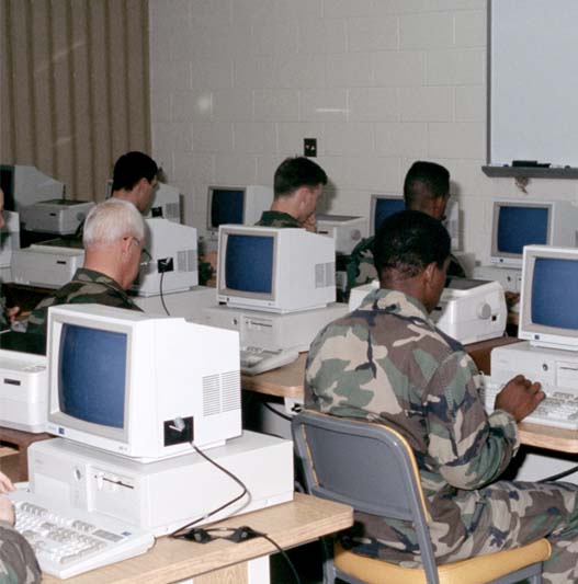 Five soldiers sitting in front of computers.