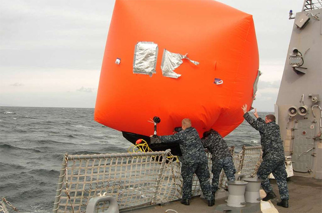 Sailors throw the 'killer tomato', an inflatable target, off the flight deck during a gunnery exercise.