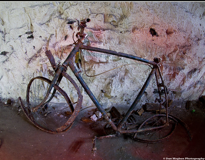 Rusted, ruined bike without tires in old tunnel