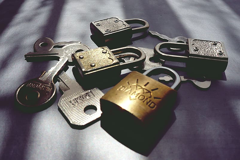 A pile of four padlocks and five keys.