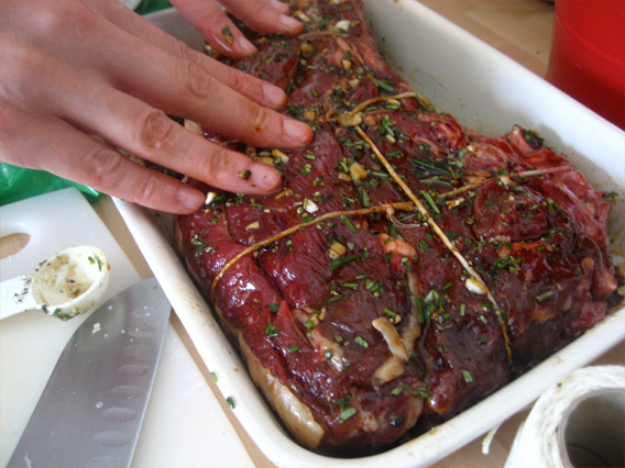 Slab of beef tied in string and marinating in a pan with a marinade