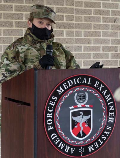 A masked soldier in camouflage uniform stands at a podium.