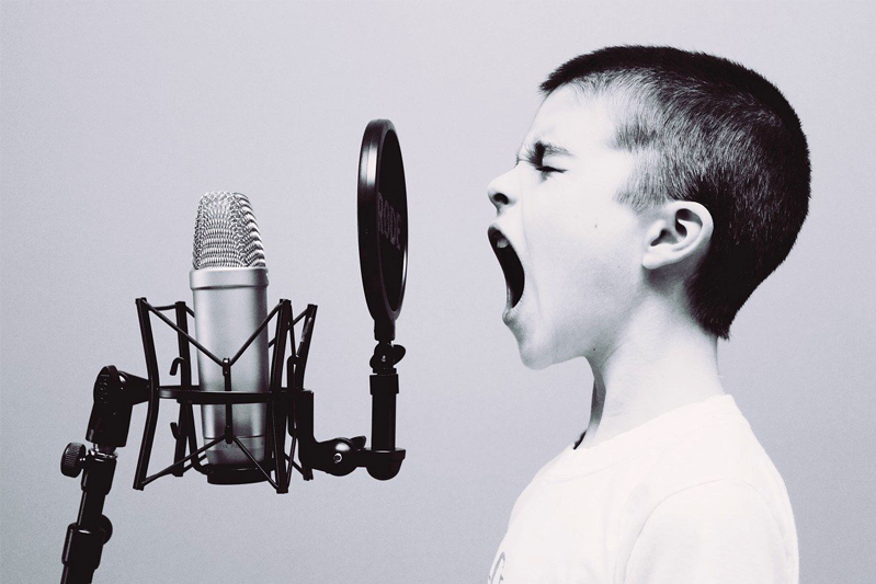 Profile of a boy screaming into an old-fashioned mic