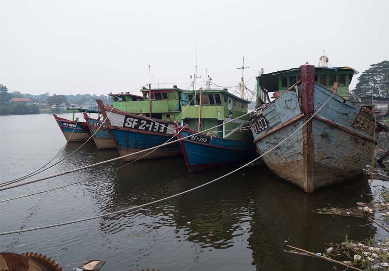 Five old fishing boats tied up with ropes.