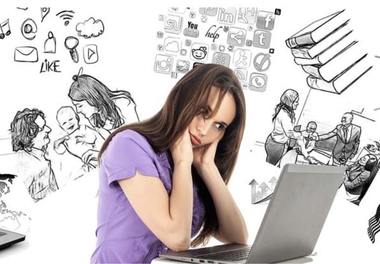 A woman with long brown hair wearing a purple T-shirt props her head up with both hands while staring at her computer, as graphic images of multiple projects revolve around her head.