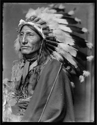 A black-and-white photo of a Native American wearing a headdress.