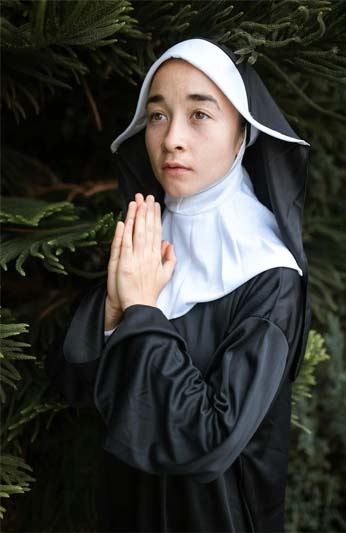 A close-up of a young nun praying.
