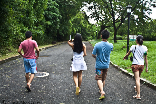 Two boys and two girls walk down an asphalt path in a park.