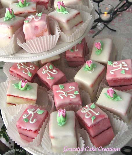 A double-tiered plate filled with pink and white tiny cakes.