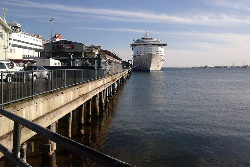 Cruise ship tied up alongside a pier with buildings on it.