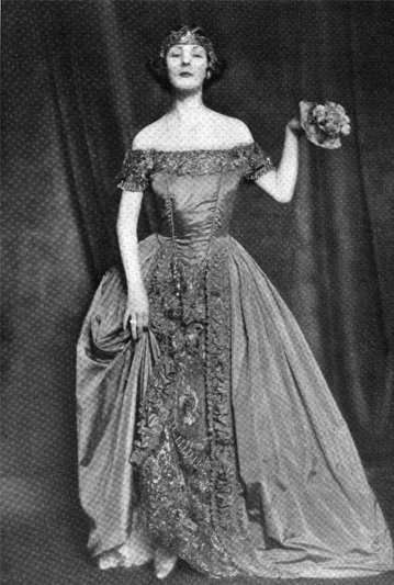 An old black-and-white photo of a dancer in a long dress holding a nosegay