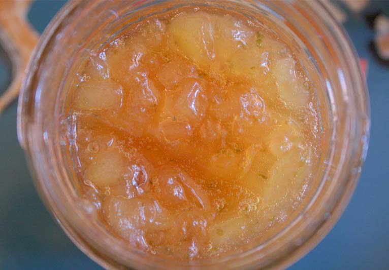 A close-up view looking straight down into a jar of peach preserves.