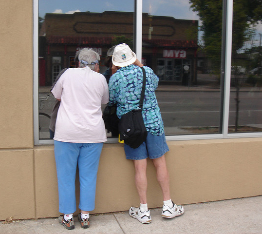 An old couple prying into a darkened shop window