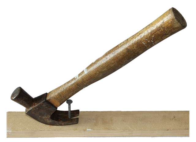 Claw of hammer placed around a nail stuck in a piece of wood