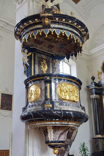 A highly decorated pulpit in blues and gold built onto a wall
