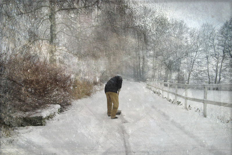 Man shoveling a path in a long, long driveway