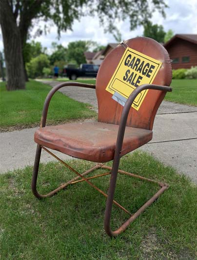 Garage Sale sign taped to old red metal chair.