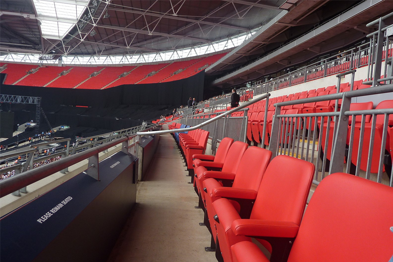 A side-on view of the two blue and multiple red seats for the queen and her party at a stadium