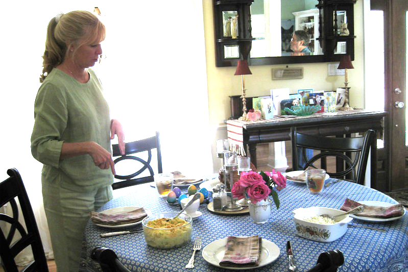 A woman is setting a blue-and-white checked tablecloth for five